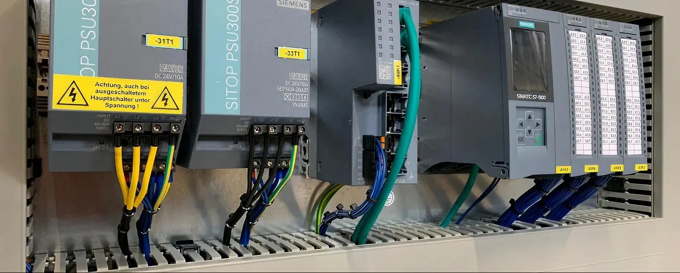 Siemens SITOP Netzteile und eine Simatic S7-1500 auf der Hutschiene, mit Warnhinweis zur Spannung