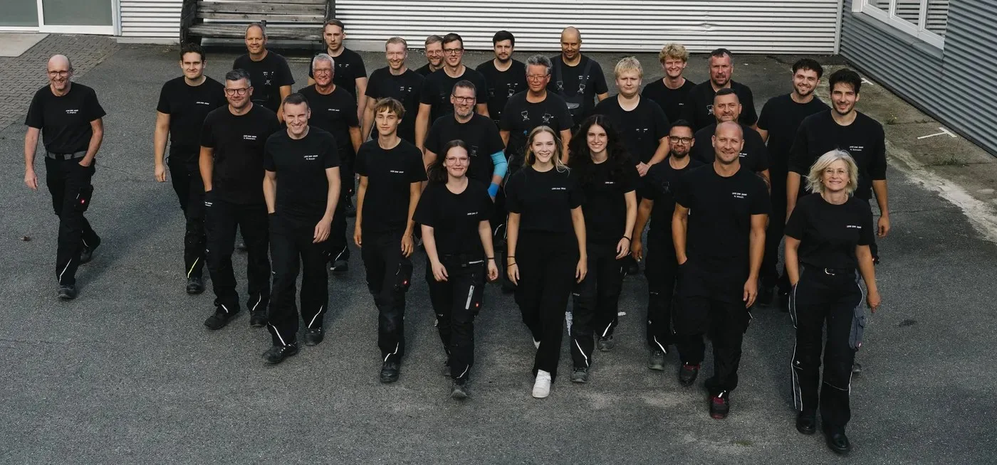 Das Team läuft in Arbeitskleidung über den Hof auf die Kamera zu