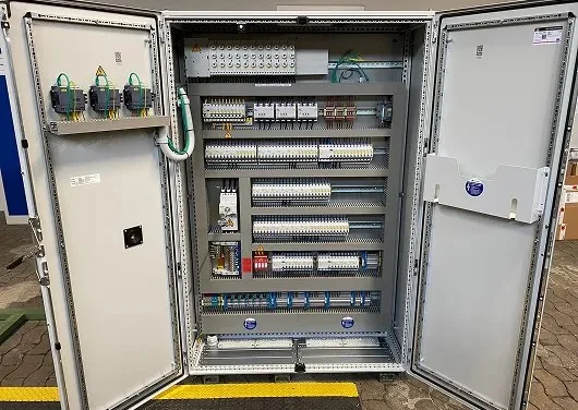 Geöffneter zweitüriger Schaltschrank mit Reihen von Bauteilen und Klemmen