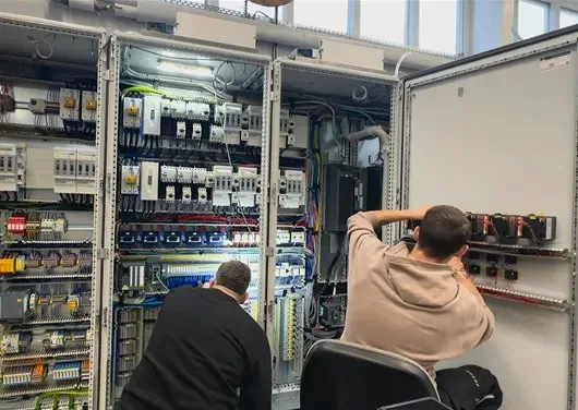 Zwei Monteure arbeiten an einer geöffneten Schaltschrankreihe